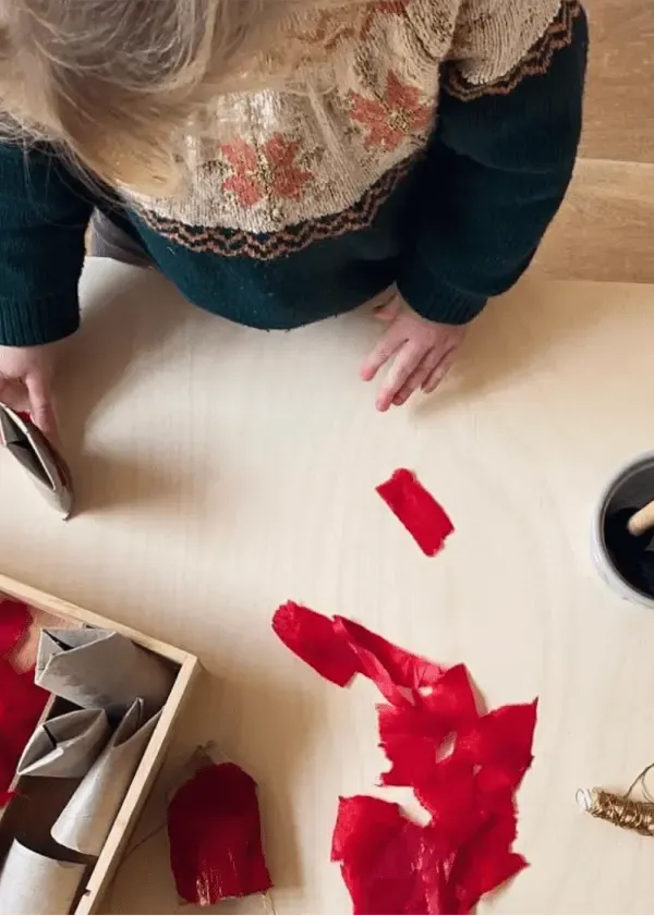 Toddler doing paper crafts on a wooden table