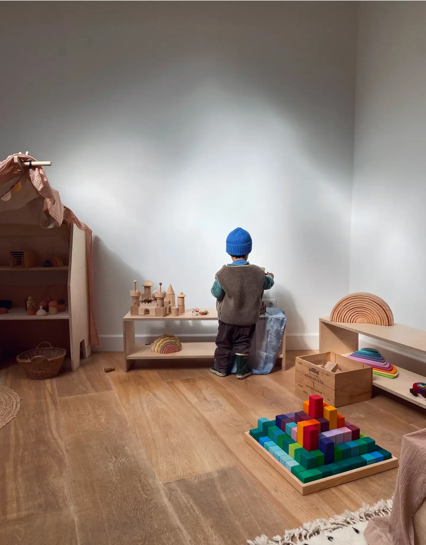 Boy wearing cosy clothes and playing with wooden toys in the playgroup