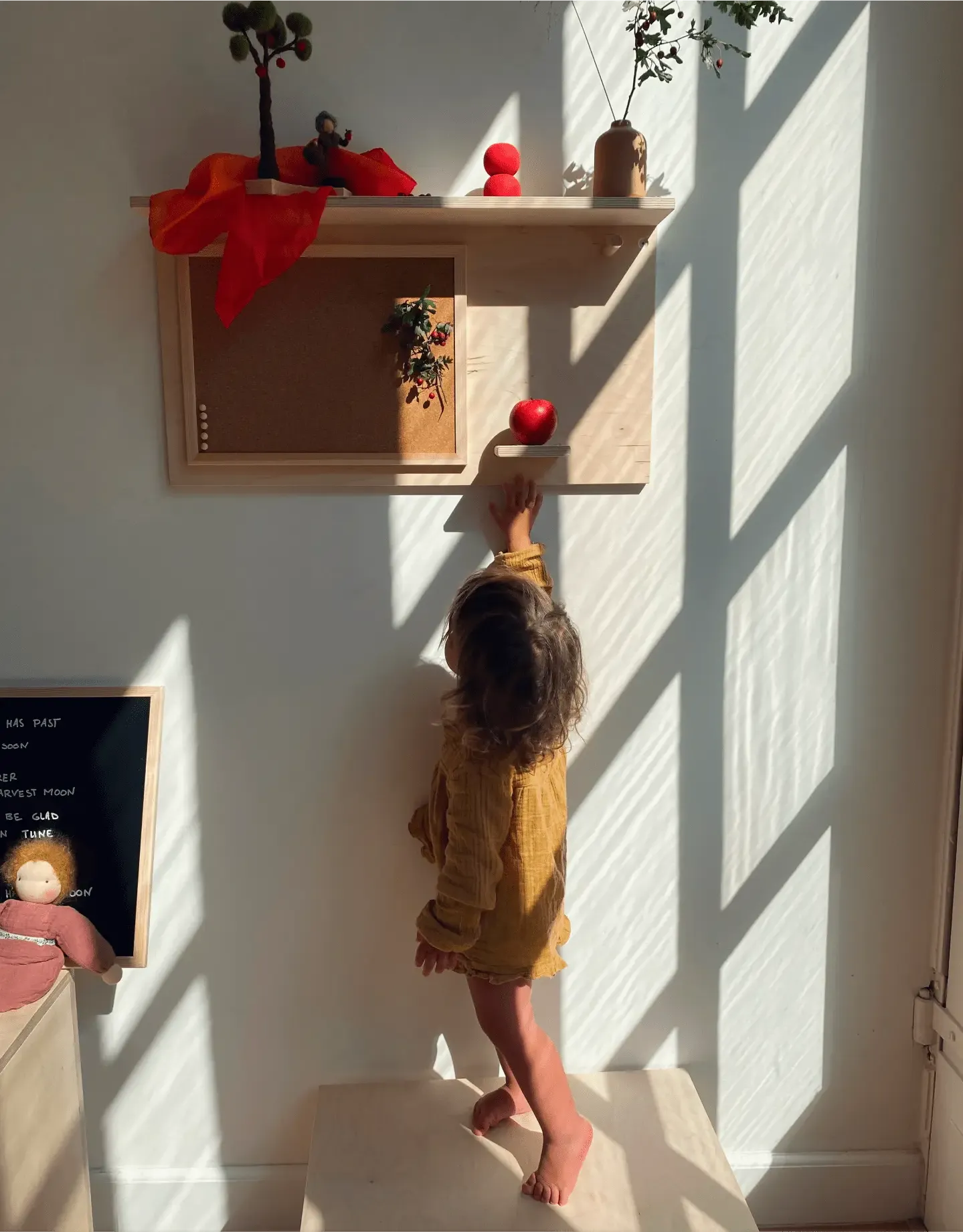 Girl reaching for a red wooden apple